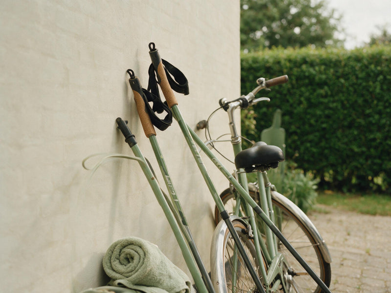 Cykel op ad en lys mur med et par gåstave ved siden af